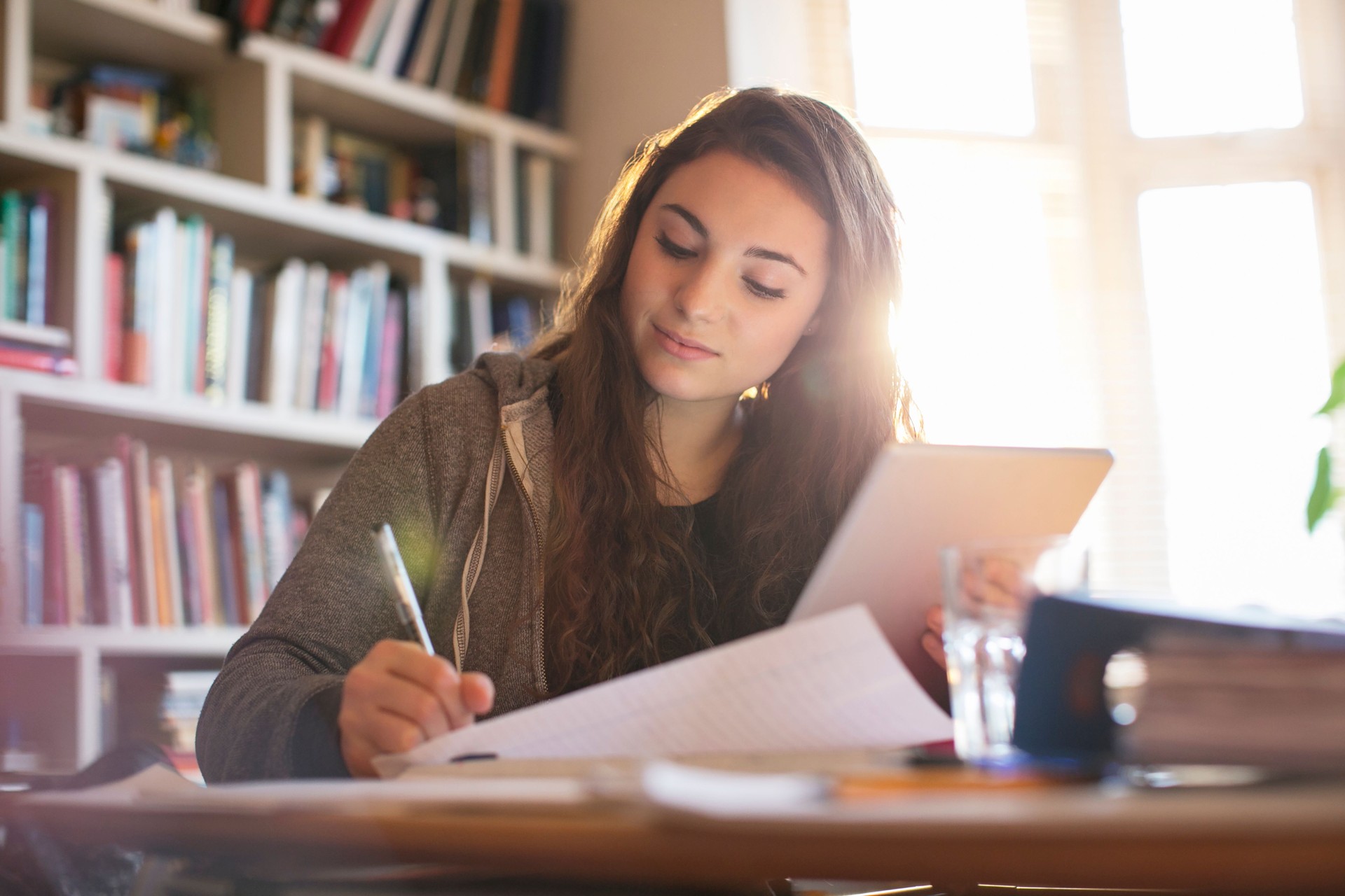 Teenage girl with digital tablet doing homework at desk